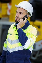 young male engineer at construction site using smart phone