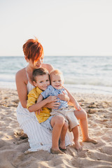 Young motherand her little sons on beach at sunset