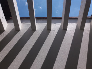 shadows forming on the parade in a conservatory with concrete pergola with a very blue sky