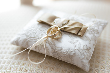 Golden wedding rings lies on a small decorated pillow 