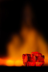 Red hot coal bars in focus on dark background with flames. Background of raw coal with soft focus exclusion with color and temperature.