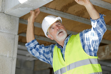 senior man inspecting lintel on construction site - obrazy, fototapety, plakaty