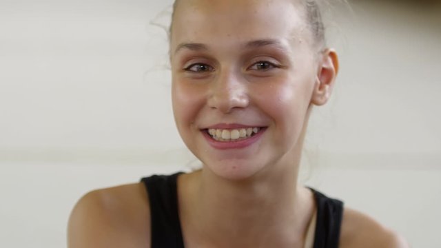Close up portrait of adorable young teenage girl looking at camera and smiling in gymnastics class