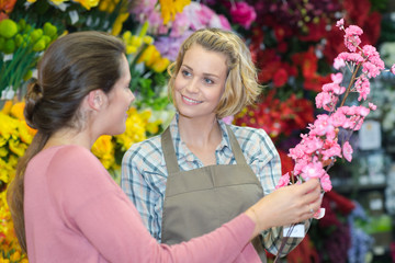 Obraz na płótnie Canvas young smiling woman selecting plastic flowers