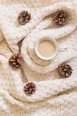 Cozy winter coffee composition with white sweater and pine cones. Flat lay, top view