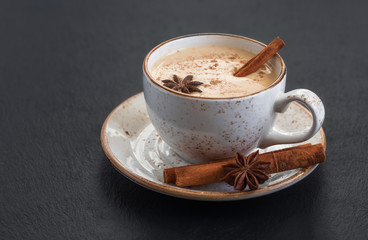 Indian Masala chai tea. Traditional Indian hot drink with milk and spices on dark stone background...