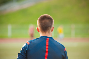 Assistant soccer referee standing with his back against the backdrop of a soccer field with players