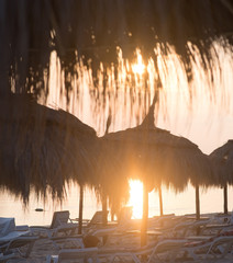 Tiki hut umbrellas, thatch. Sunrise view on beach in Tunisia