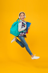 Fototapeta na wymiar Getting back into studying. Energetic little girl run to school yellow background. Small child with school bag and books back to class. Back to school time. Happy welcome back