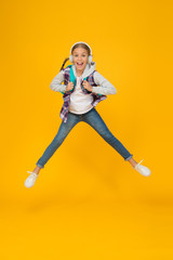 Fototapeta na wymiar Energetic and enthusiastic. Energized small girl jump high with energetic power. Active kid back to school in energetic mood. Energetic little child in motion yellow background