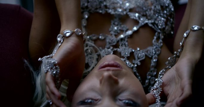 Close-up portrait of a sexy girl model, she lies in the Studio and poses, her silver unusual underwear. She's covered in silver jewelry.