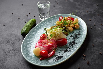 Marinated vegetables with mushrooms and a glass of vodka on a dark background