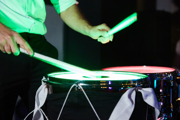 Close-up of the hands of a drummer playing light drums in the dark. shallow depth of field