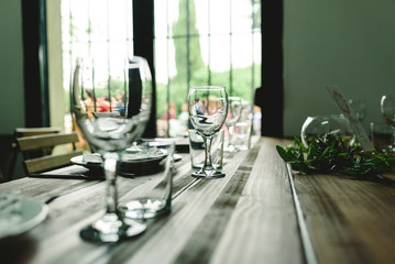 Wooden tables with cutlery plates and backlit glasses without anyone.