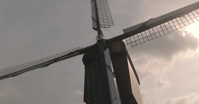 Old windmill spinning in the wind, sunlight flares through the sails