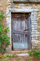 Old locked wooden door on a stone abandoned farmhouse. Image