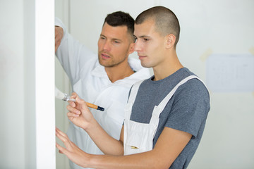 young male apprentice brushing the wall with paint