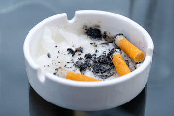 White dirty ashtray with cigarette stubs. Cigarette.