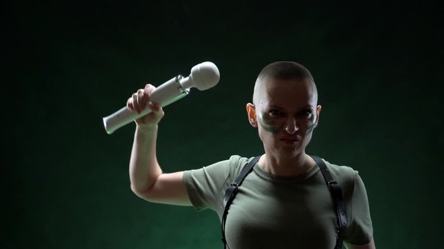 brutal bald woman with camouflage makeup holds a white massager in her hand
