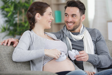 Obraz premium happy pregnant couple holding baby shoes
