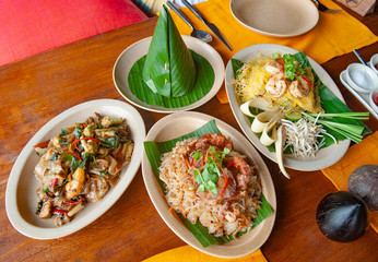 Presenting a set of popular thai foods, Pad Thai (Right), Yum Som O or Pomelo Salad (Middle). Pad Kee Mao (Left) and coned banana leaves cover the steamed rice. 