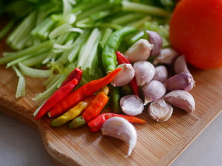Selective focus of fresh chilies and garlics on a wooden cutting board prepared for cooking