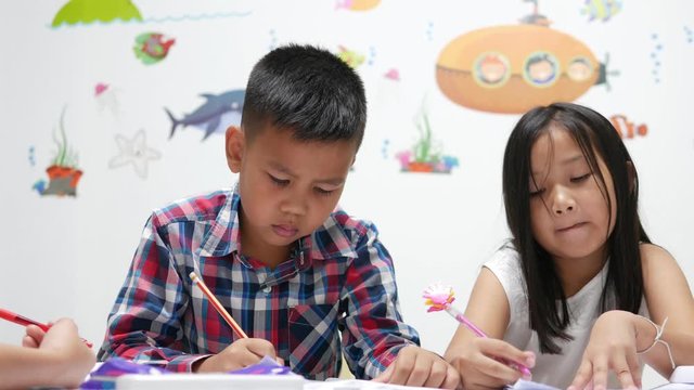  A male Asian elementary school students are studying mathematics by counting their fingers, helping to do exercises with Asian female teacher.