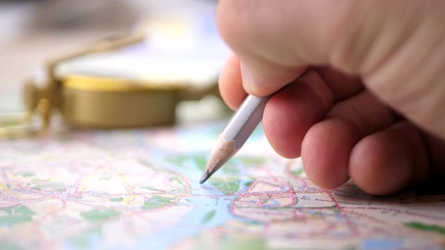 Men's finger planning river rafting trip on a map with compass. Finding your way concept
