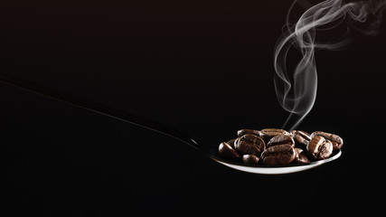 beverage background of roasted coffee beans in spoon isolated on dark background with aromatic smoke
