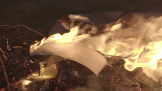 Vintage book page burning in fire flame at night, burn secret old note in bonfire outdoor 
