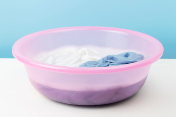 White and blue clothes washed with a basin with soap bubbles, close-up