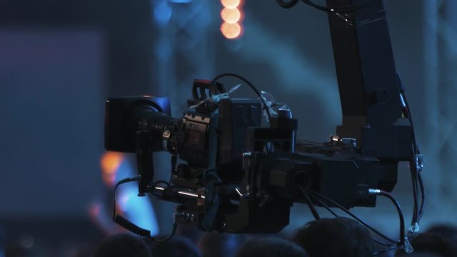 View of professional camera shoots a concert at dark video performance stage festival people rock event nightlife popular entertainment fun light show technology band singer media recording