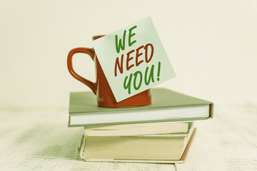 Conceptual hand writing showing We Need You. Concept meaning to fulfill the needs of the assignment duty or obligation Coffee cup sticky note stacked books retro old retro wooden table