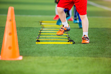 Kid soccer player Jogging and jump between marker for football training. Ladder drills exercises...