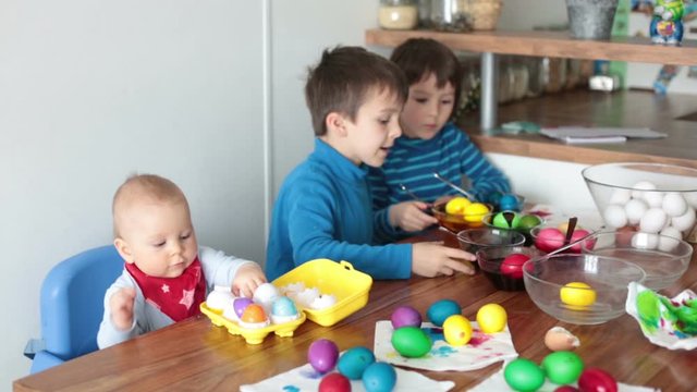 Three children, coloring and painting easter eggs at home for the holiday