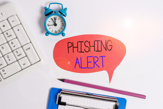 Word writing text Phishing Alert. Business photo showcasing aware to fraudulent attempt to obtain sensitive information Flat lay above table with clock pc keyboard and copy space note paper