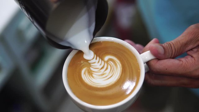 barista pouring milk to make coffee latte art. b-roll footage video 4k. cafe business shop.