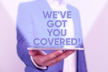 Writing note showing We Ve Got You Covered. Business concept for have done gotten or provided whatever needed Man in the blue suite and white shirt holds mobile phone in the hand