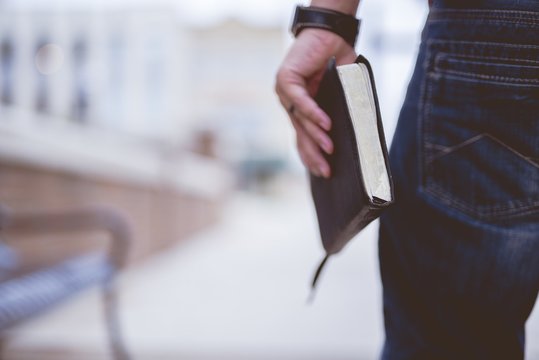 Closeup shot of a male holding the bible with a blurred background
