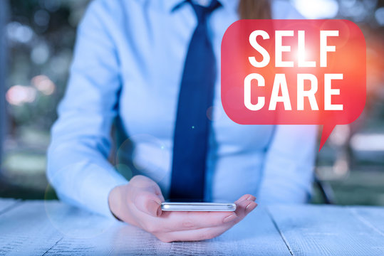 Writing Note Showing Self Care. Business Concept For The Practice Of Taking Action To Improve One S Is Own Health Female Business Person Sitting By Table And Holding Mobile Phone