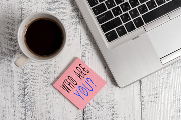 Handwriting text writing Who Are You Question. Conceptual photo asking about someone identity or demonstratingal information Trendy metallic laptop blank sticky notes coffee cup lying vintage table