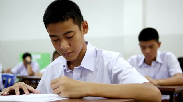 Asian high school students in white uniform are doing examinations.