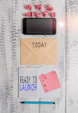 Handwriting text writing Ready To Launch. Conceptual photo an event to celebrate or introduce something new to market Envelop smartphone notepad note clip marker paper balls wooden background