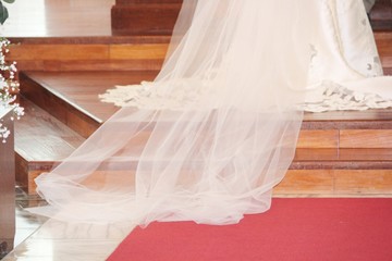 Long lace trail of a wedding gown with red carpet