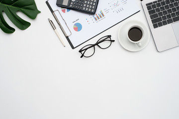 Top view business finance office concept on white table desk with Laptop computer and graph document, calculator and supplies, flat lay with copy space