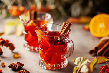 Mulled wine with fruits and spices in glass on a wooden  background. Traditional hot drink at  Autumn time