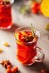 Mulled wine with fruits and spices in glass on a wooden  background. Traditional hot drink at  Autumn time