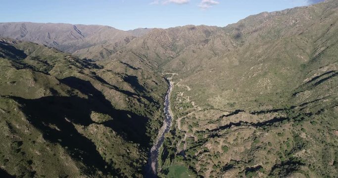 Aerial drone scene traveling along river valley, panoramic view of forest on mountain chains. Wild natural lanscape. Rio Grande touristic destination, Nogoli, San Luis, Argentina