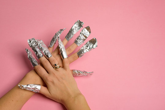 The procedure for removing varnish from nails hybrid nails in progress. Gel nail polish remover foils on woman's hands.
