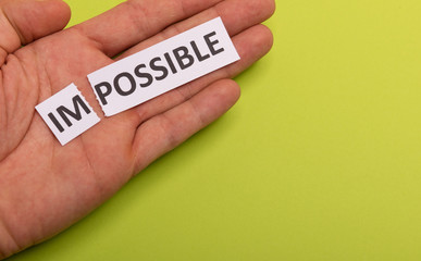 Impossible text cut out in hand. Possible concept. Success. Pink background. Copy space. Vertical orientation. View from above. Minimal simple style.